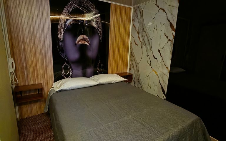 Habitación climatizada de Motel Match con cama de dos plazas, mural decorativo y terminaciones remodeladas